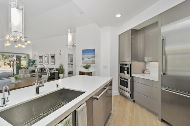 kitchen featuring appliances with stainless steel finishes, pendant lighting, sink, gray cabinetry, and light wood-type flooring