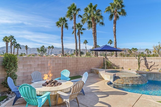 view of patio featuring a swimming pool with hot tub, a mountain view, a fire pit, and pool water feature