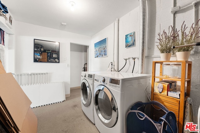 clothes washing area with light carpet and washer and dryer