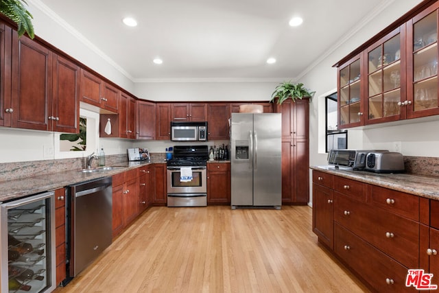 kitchen featuring wine cooler, sink, crown molding, appliances with stainless steel finishes, and light stone countertops