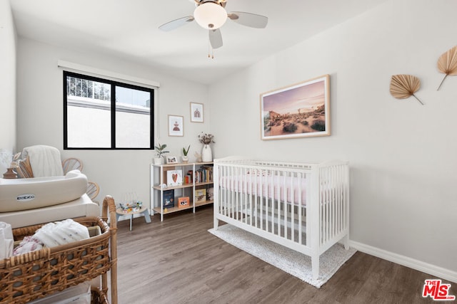 bedroom with ceiling fan, dark hardwood / wood-style floors, and a nursery area