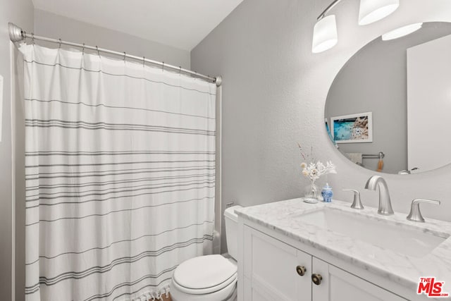 bathroom with vanity, curtained shower, and toilet