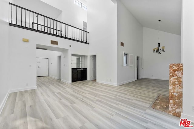 unfurnished living room featuring an inviting chandelier and light wood-type flooring