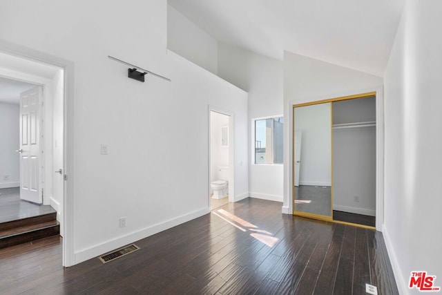 unfurnished bedroom with connected bathroom, a closet, high vaulted ceiling, and dark hardwood / wood-style floors