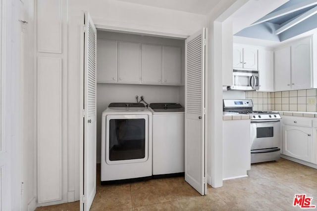 laundry area featuring cabinets, light tile patterned flooring, and washer and clothes dryer