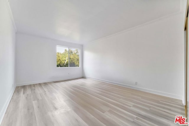 empty room featuring ornamental molding and light hardwood / wood-style floors