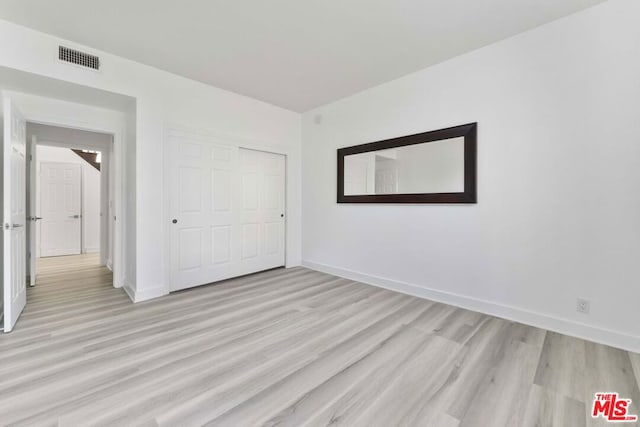 unfurnished bedroom with light hardwood / wood-style floors and a closet