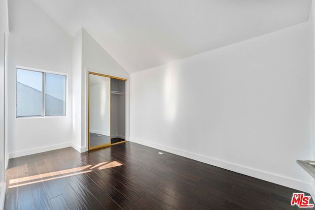 unfurnished bedroom with dark hardwood / wood-style flooring, high vaulted ceiling, and a closet