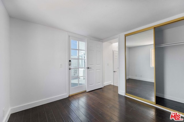 unfurnished bedroom featuring dark hardwood / wood-style floors and a closet