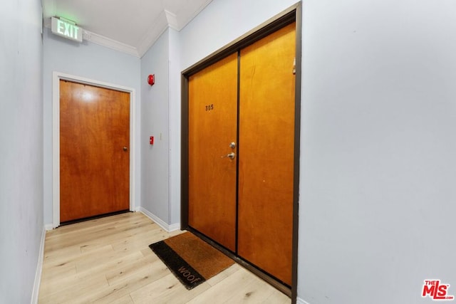 doorway with ornamental molding and light wood-type flooring