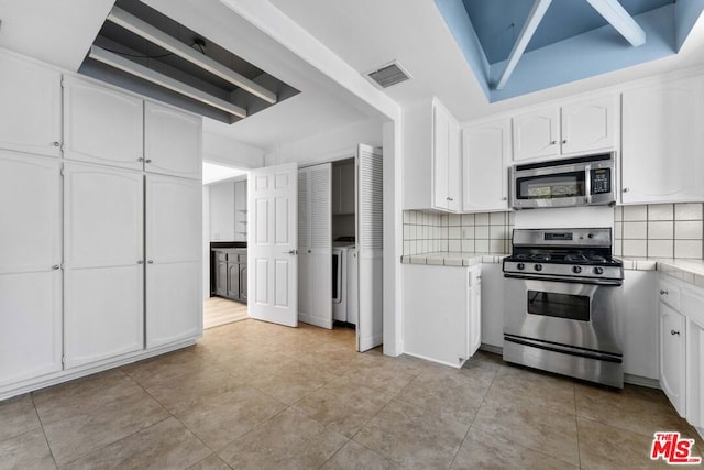 kitchen featuring stainless steel appliances, white cabinetry, light tile patterned floors, and decorative backsplash