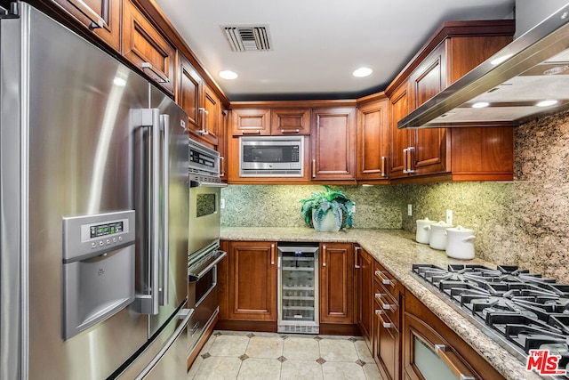 kitchen with tasteful backsplash, beverage cooler, light stone counters, stainless steel appliances, and wall chimney exhaust hood