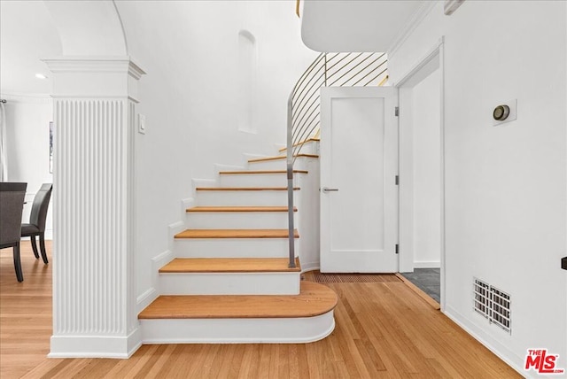 staircase featuring crown molding and hardwood / wood-style floors