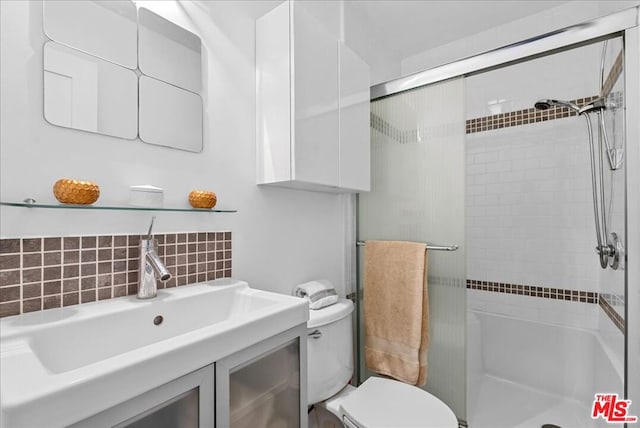 bathroom featuring tasteful backsplash, walk in shower, toilet, and sink