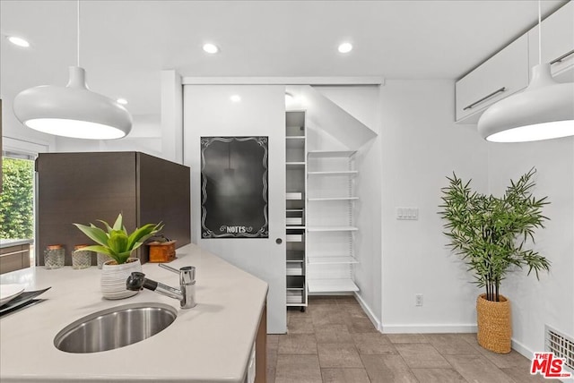 kitchen with white cabinetry, sink, and pendant lighting