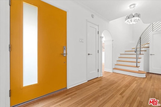 entryway with crown molding, an inviting chandelier, and light wood-type flooring