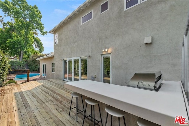 back of house with area for grilling, a swimming pool side deck, and exterior bar