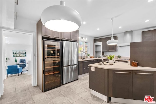 kitchen featuring sink, decorative light fixtures, dark brown cabinets, stainless steel refrigerator, and beverage cooler