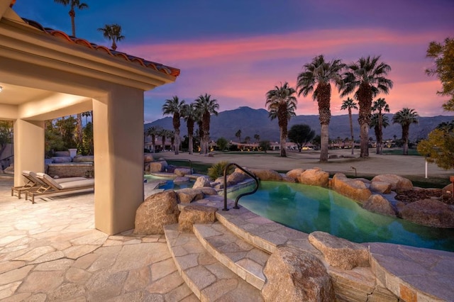 pool at dusk with a mountain view and a patio area