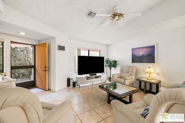 living room featuring ceiling fan, vaulted ceiling, a textured ceiling, and light tile patterned flooring