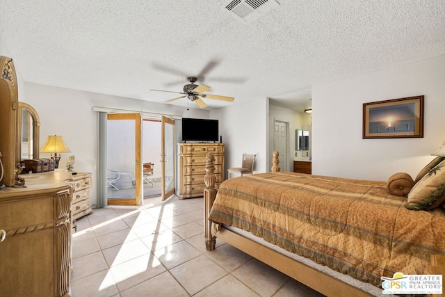 bedroom with light tile patterned floors, ceiling fan, access to exterior, connected bathroom, and a textured ceiling