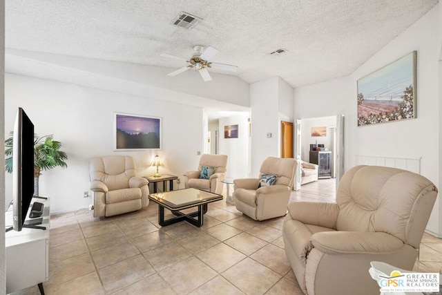 tiled living room with lofted ceiling, ceiling fan, and a textured ceiling