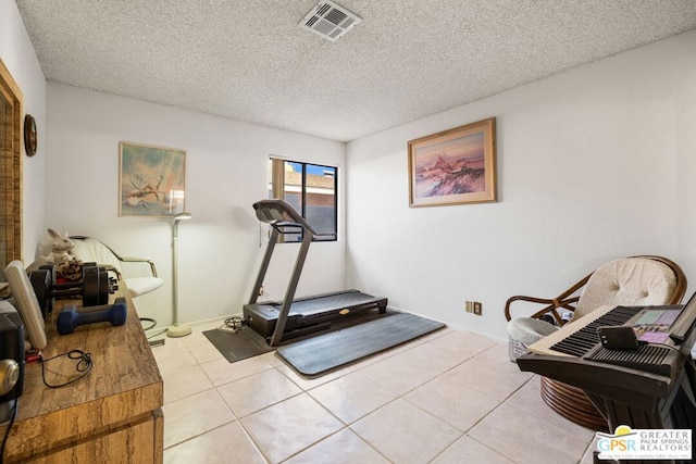 workout room featuring light tile patterned floors and a textured ceiling