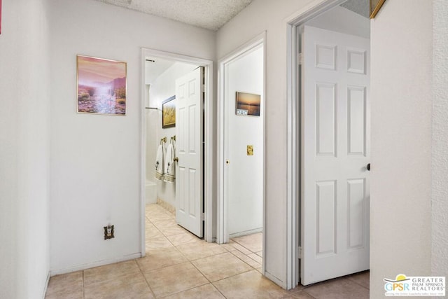 hallway with light tile patterned floors and a textured ceiling