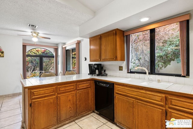 kitchen with tile countertops, black dishwasher, sink, kitchen peninsula, and a textured ceiling