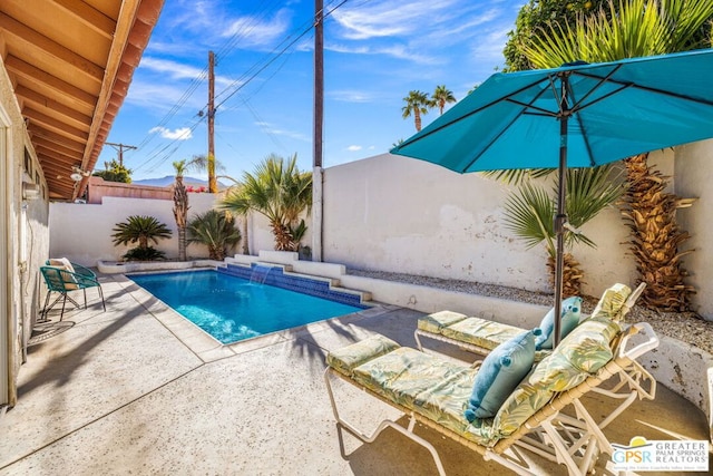 view of swimming pool with pool water feature and a patio