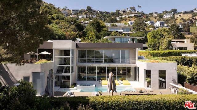 back of house featuring a swimming pool with hot tub and a patio area