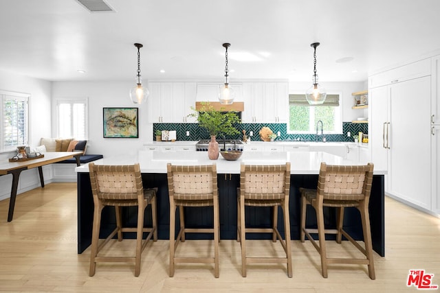 kitchen featuring tasteful backsplash, a kitchen island, a breakfast bar area, and white cabinets