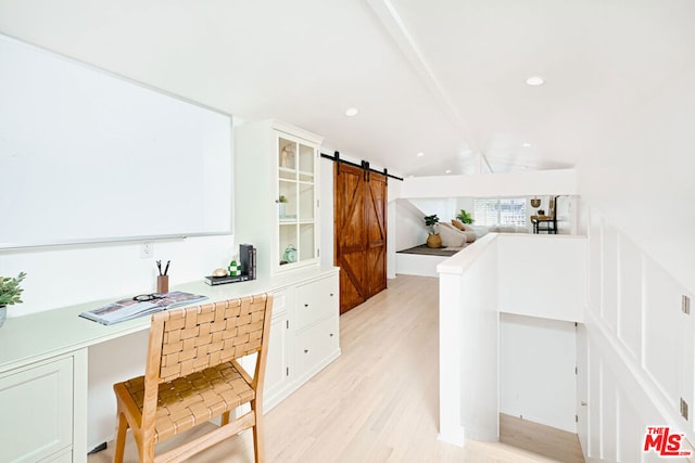 kitchen with built in desk, lofted ceiling, white cabinets, a barn door, and light wood-type flooring