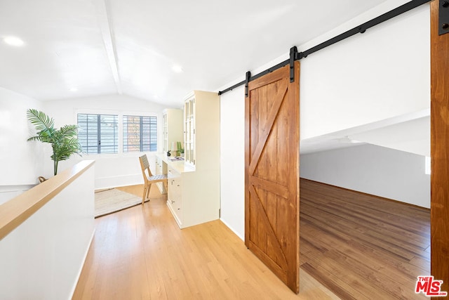 hall featuring vaulted ceiling with beams, a barn door, and light wood-type flooring