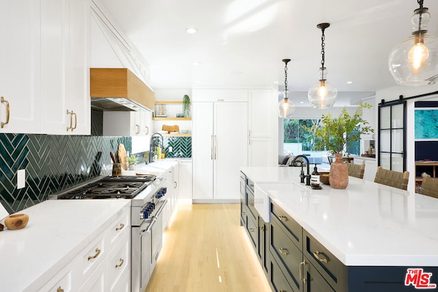 kitchen featuring hanging light fixtures, backsplash, white cabinets, and light wood-type flooring