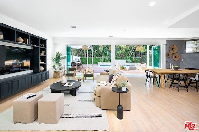 living room featuring crown molding, light wood-type flooring, and built in shelves