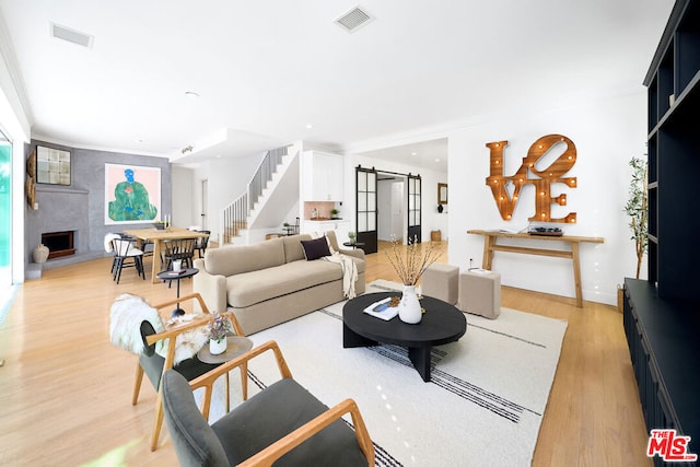 living room featuring a fireplace, light hardwood / wood-style floors, and a barn door