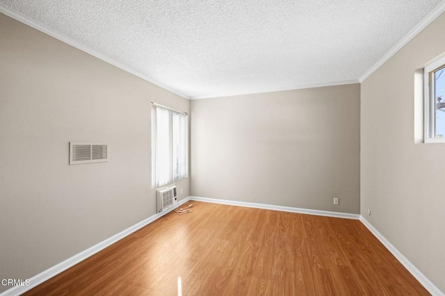 unfurnished room with hardwood / wood-style floors, ornamental molding, and a textured ceiling