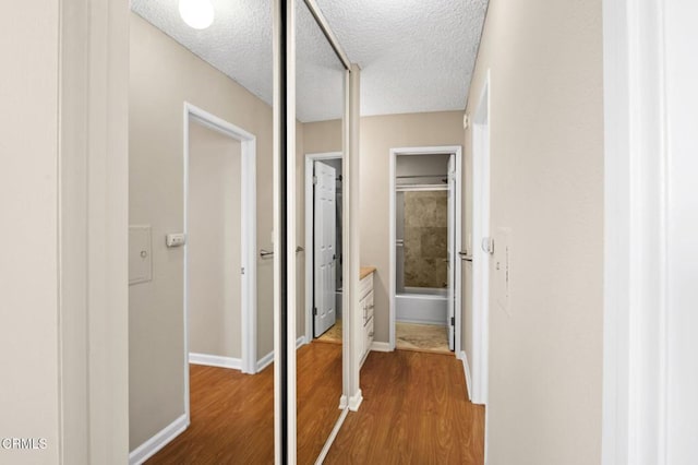 hallway with hardwood / wood-style floors and a textured ceiling