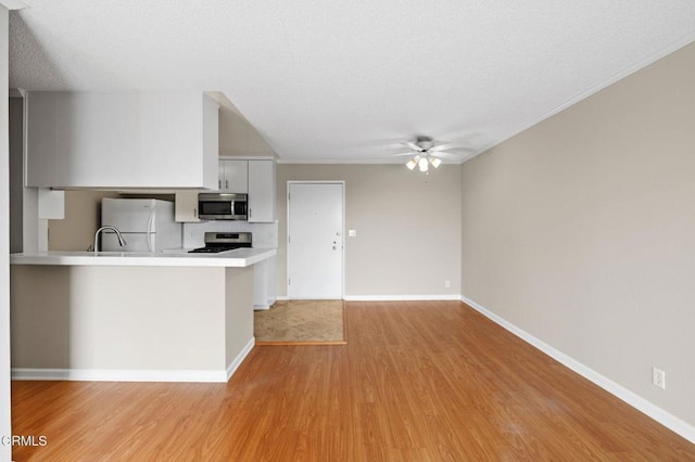 kitchen featuring appliances with stainless steel finishes, kitchen peninsula, white cabinetry, ceiling fan, and light hardwood / wood-style floors