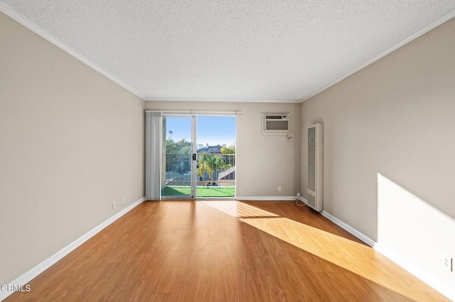 spare room with hardwood / wood-style flooring, ornamental molding, a wall unit AC, and a textured ceiling