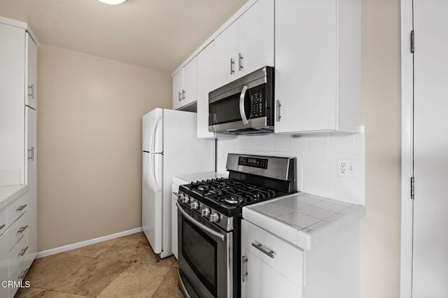 kitchen with backsplash, stainless steel appliances, tile counters, and white cabinets