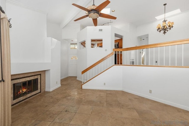 unfurnished living room featuring a tiled fireplace, ceiling fan with notable chandelier, vaulted ceiling, and crown molding