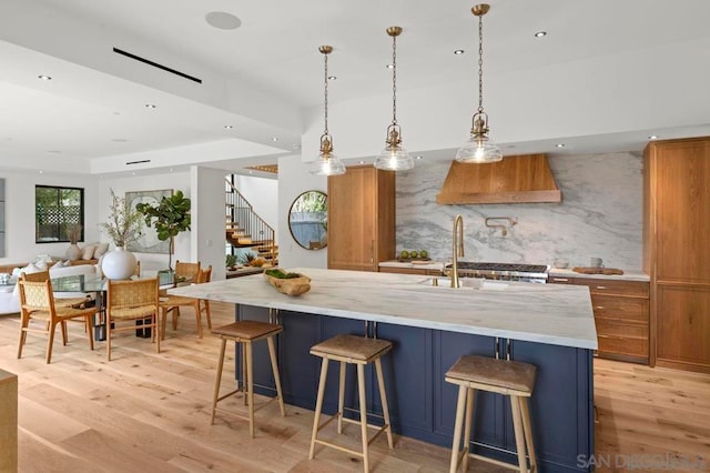 kitchen with pendant lighting, backsplash, a spacious island, a kitchen bar, and light wood-type flooring