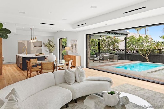 living room with sink, light hardwood / wood-style floors, and a wealth of natural light