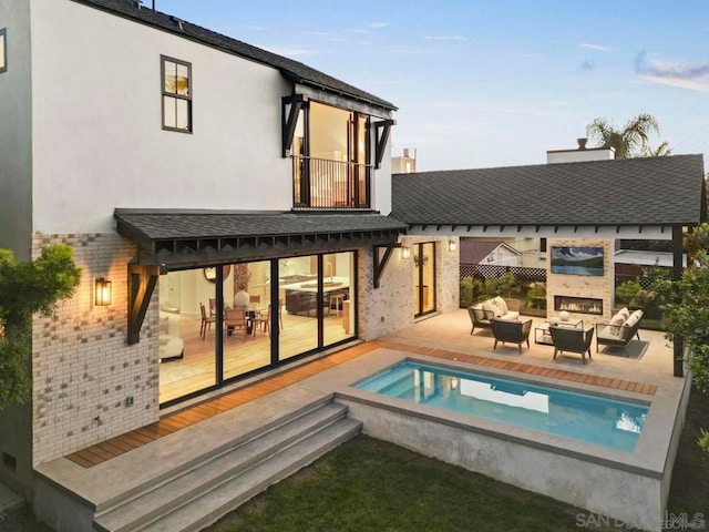 rear view of property featuring a patio, an outdoor living space with a fireplace, and a balcony