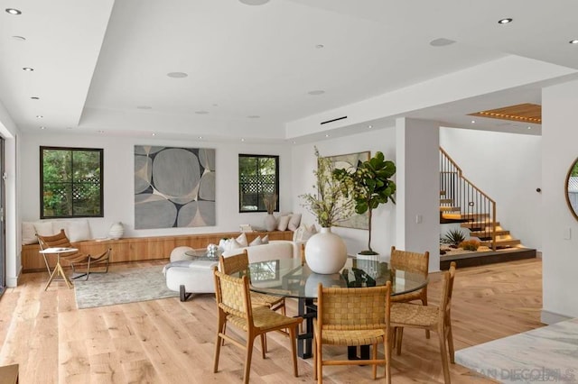 dining space with a tray ceiling and light hardwood / wood-style floors