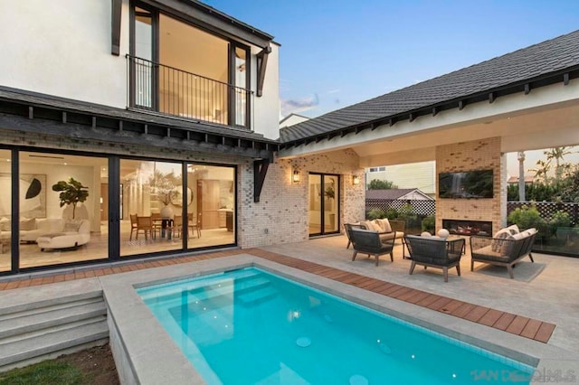 back of house with a patio and an outdoor living space with a fireplace