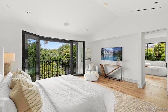 bedroom featuring lofted ceiling, access to exterior, and light wood-type flooring