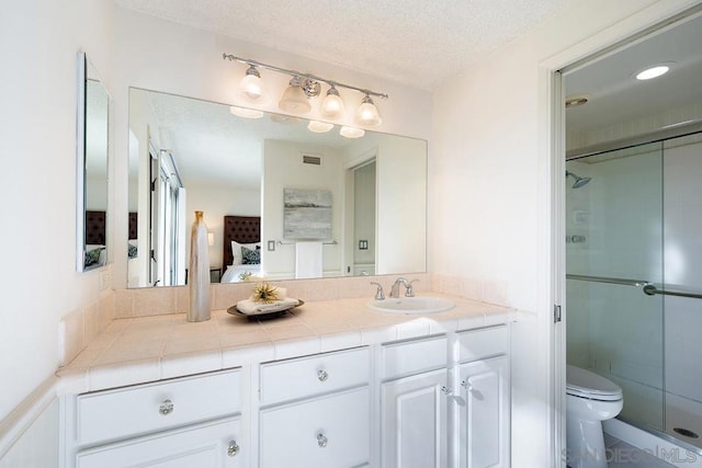 bathroom featuring walk in shower, vanity, toilet, and a textured ceiling